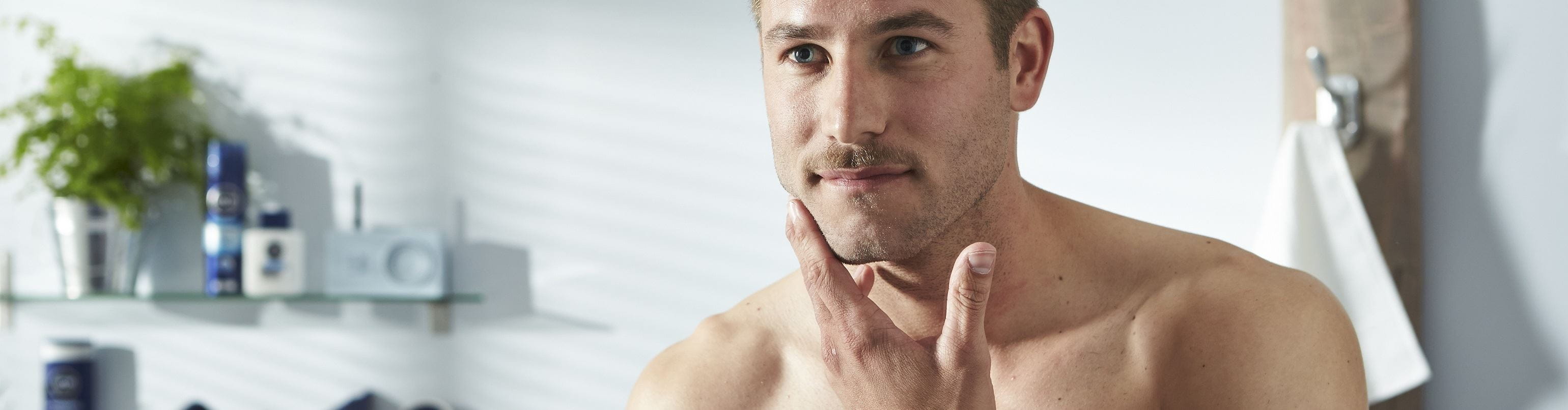 homem de bigode a ver-se ao espelho