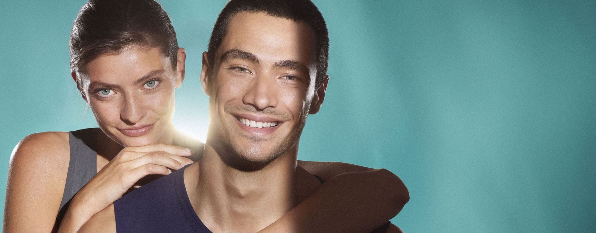 Medium close up of a woman and man, both of their faces show clear, blemish-free skin. They